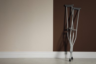 Photo of Pair of axillary crutches near color wall. Space for text