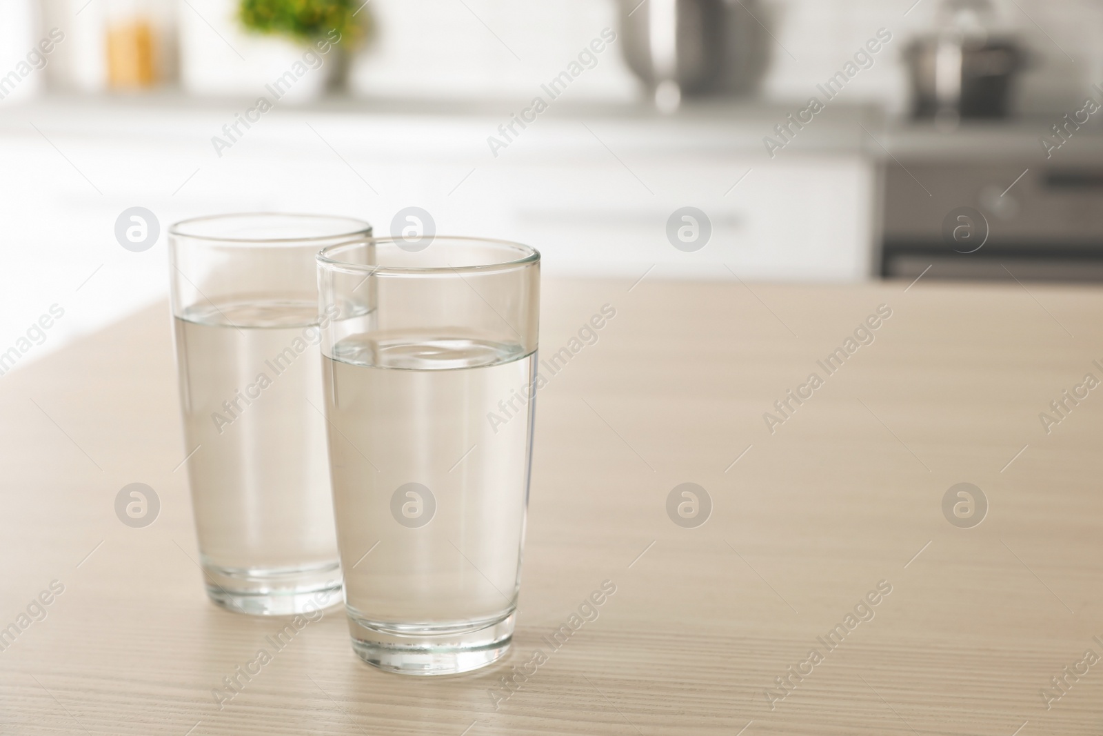 Photo of Glasses of fresh water on table indoors. Space for text