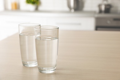 Photo of Glasses of fresh water on table indoors. Space for text