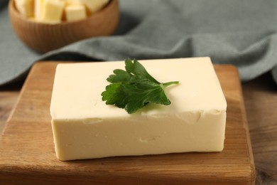 Tasty butter with parsley on wooden table, closeup