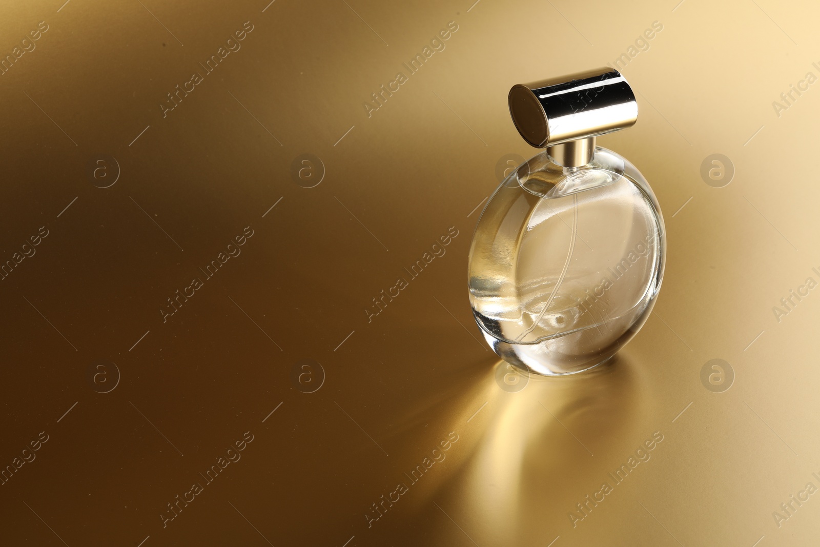 Photo of Luxury women's perfume. Sunlit glass bottle on golden background, space for text