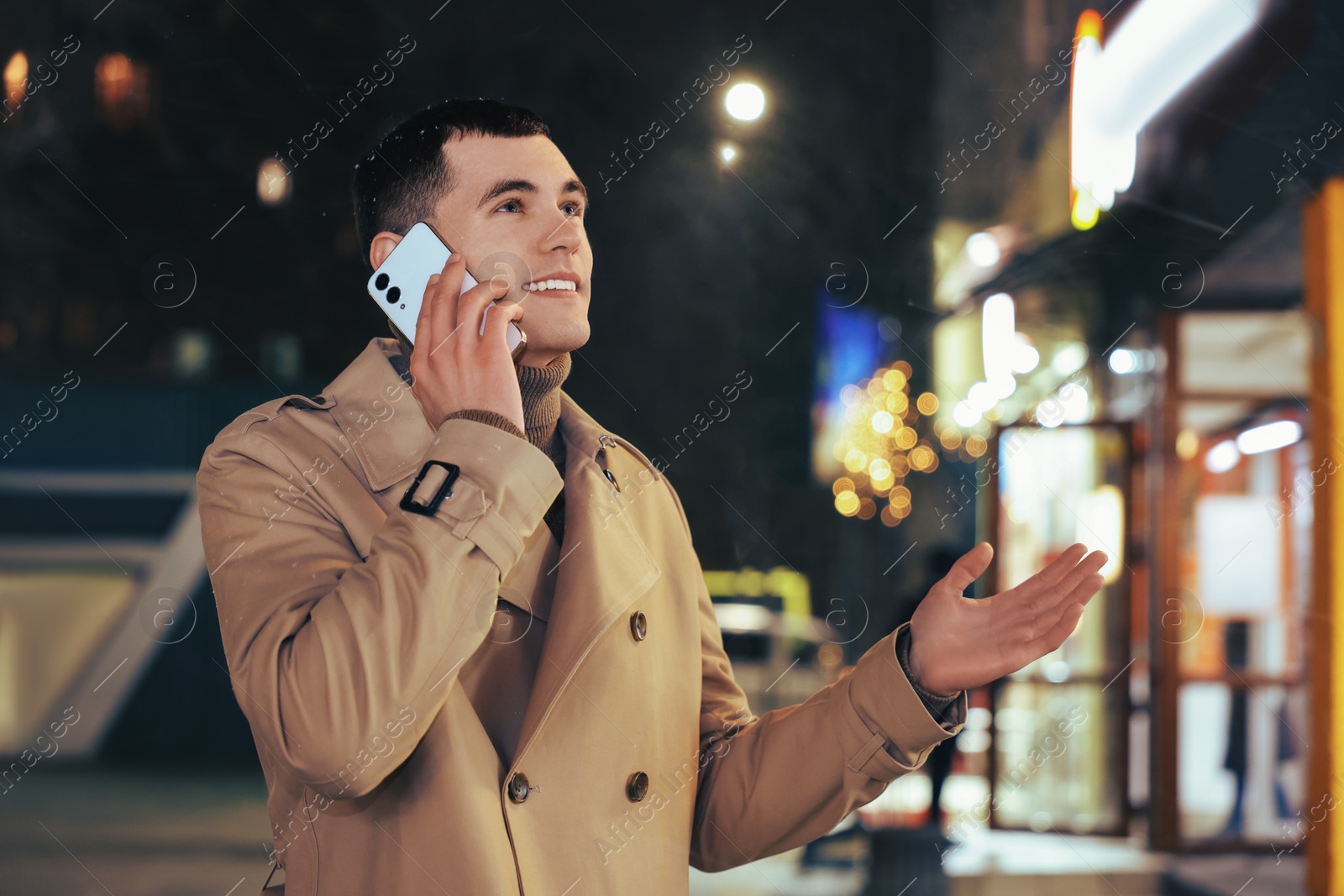 Photo of Man talking by smartphone on night city street