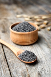 Photo of Bowl and spoon with poppy seeds on wooden table