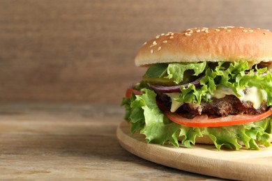 Delicious burger with beef patty on wooden table, closeup. Space for text