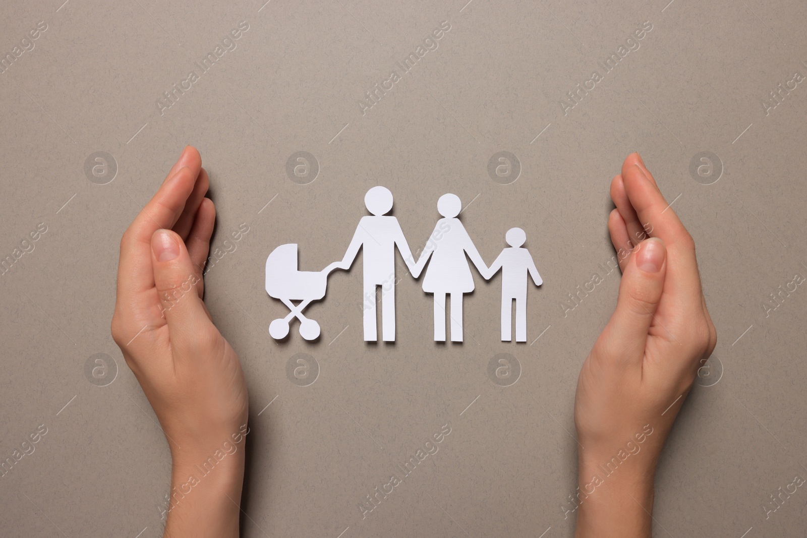 Photo of Woman protecting paper family figures on light grey background, top view. Insurance concept