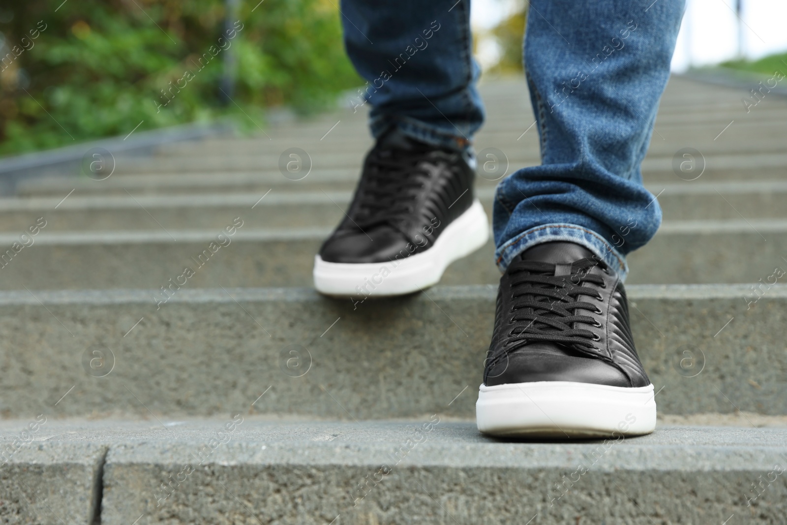 Photo of Man in stylish black sneakers walking down stairs, closeup