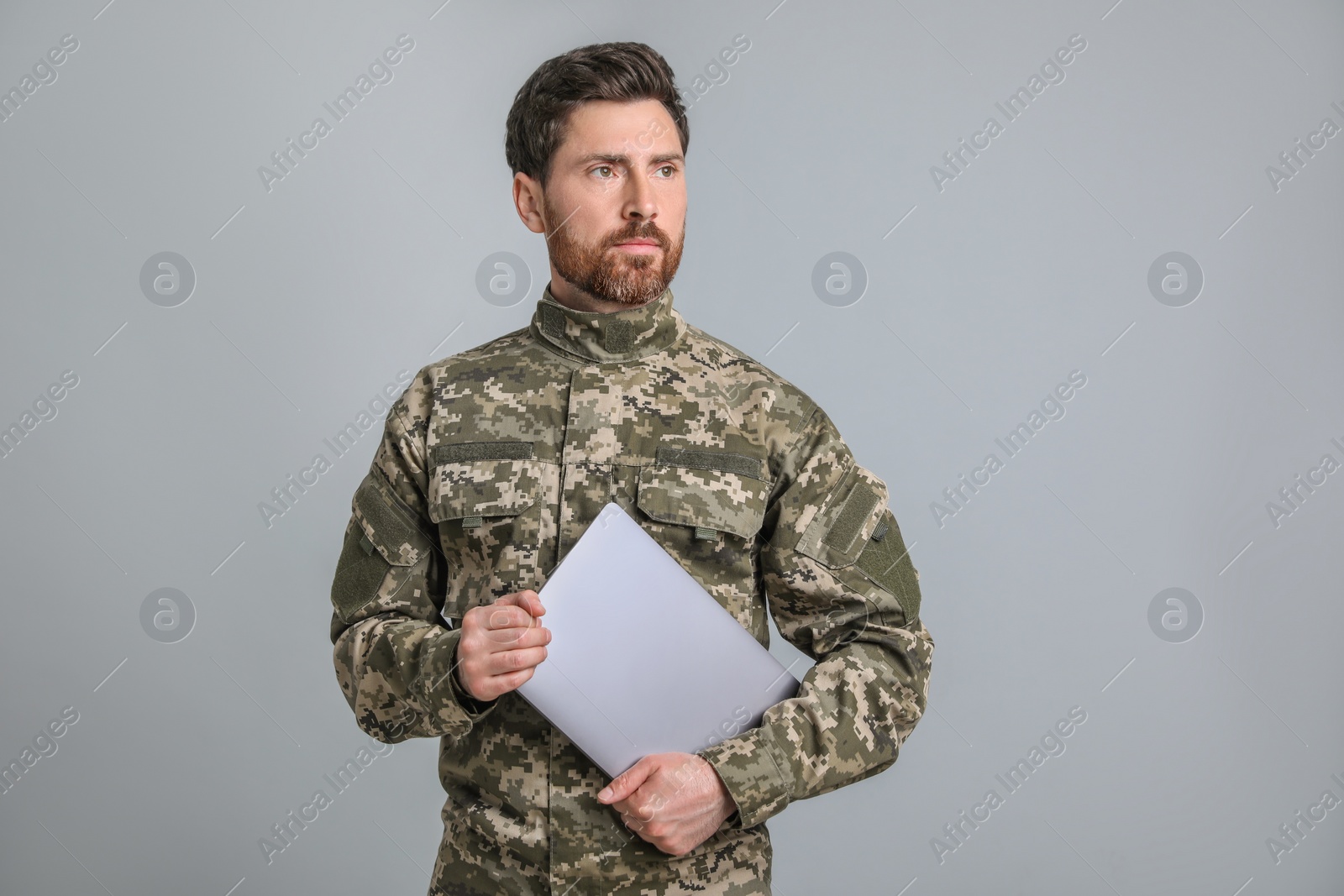 Photo of Soldier with laptop on light grey background. Military service