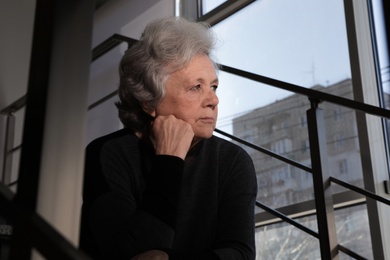 Photo of Portrait of poor mature woman sitting on stairs. Space for text