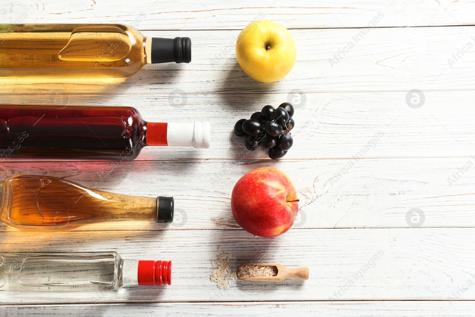 Photo of Flat lay composition with different kinds of vinegar in bottles and space for text on wooden background