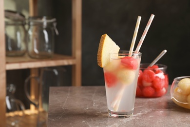 Photo of Glass with tasty melon and watermelon ball drink on table