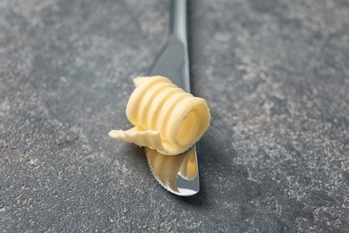 Photo of Knife with fresh butter curl on table