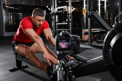 Photo of Man recording workout on camera at gym. Online fitness trainer