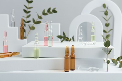 Stylish presentation of different skincare ampoules on white background