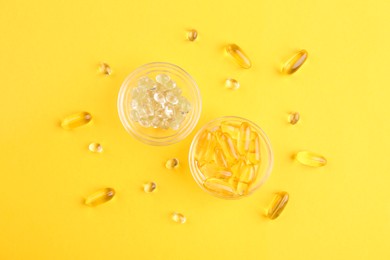 Photo of Different vitamin capsules in glass bowls on yellow background, flat lay