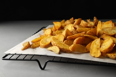 Photo of Cooling rack with delicious oven baked potatoes on table, closeup