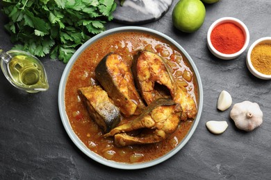 Photo of Tasty fish curry and ingredients on grey textured table, flat lay. Indian cuisine