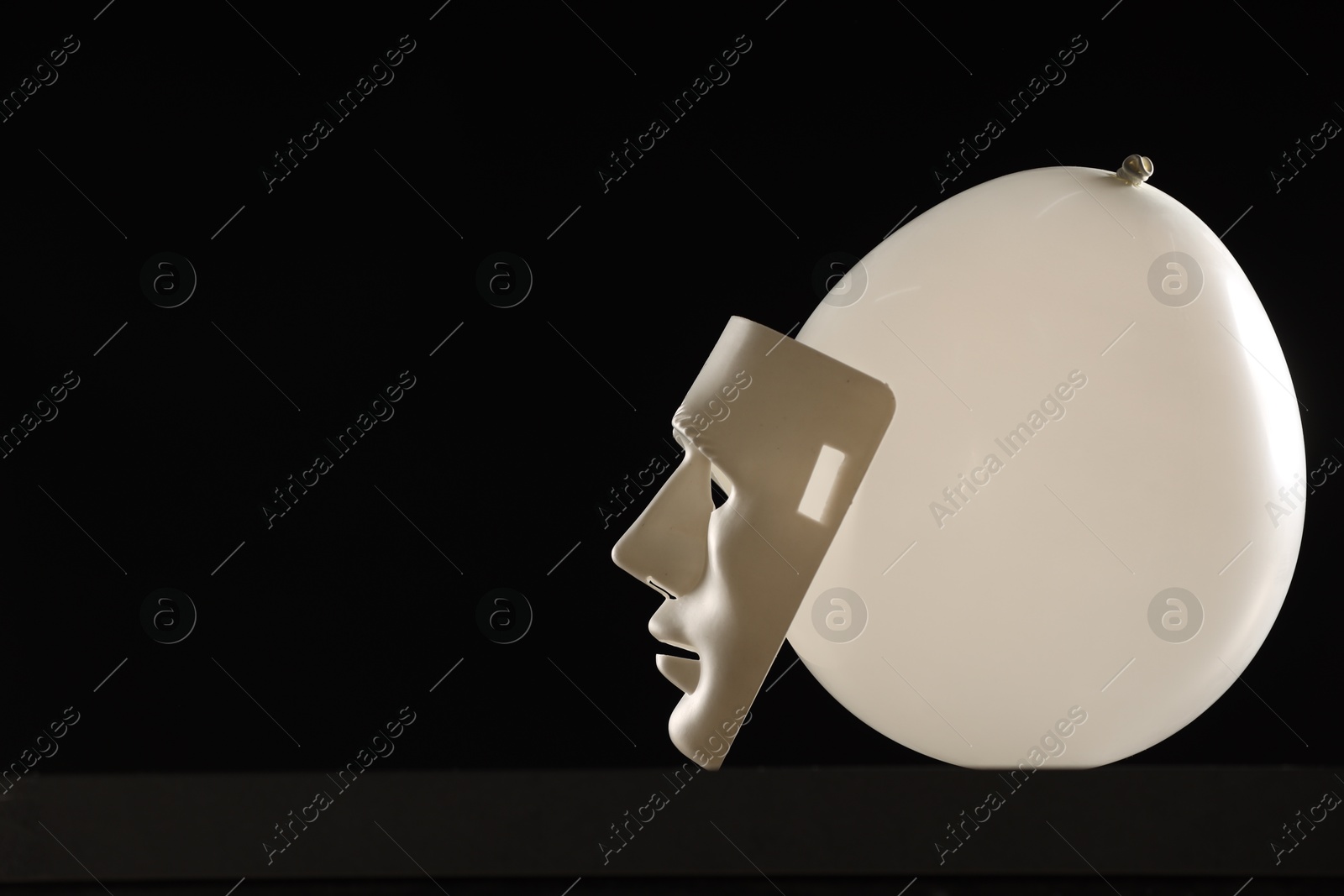 Photo of Theatrical performance. Plastic mask and white balloon on black background, space for text