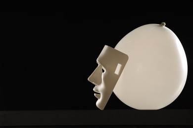 Theatrical performance. Plastic mask and white balloon on black background, space for text