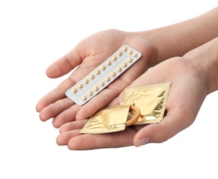 Young woman holding birth control pills and condoms on white background, closeup. Safe sex concept