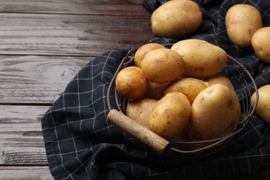 Photo of Raw fresh potatoes in metal basket on wooden table