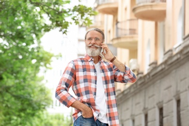 Photo of Handsome mature man with mobile phone, outdoors