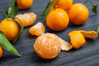 Fresh ripe tangerines with green leaves on table