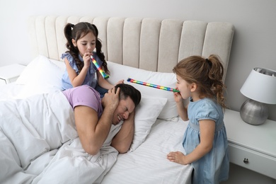 Photo of Cute little children with party blowers waking up their father at home