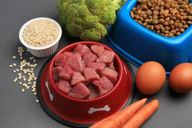 Raw meat in bowl and healthy products for pet on black background