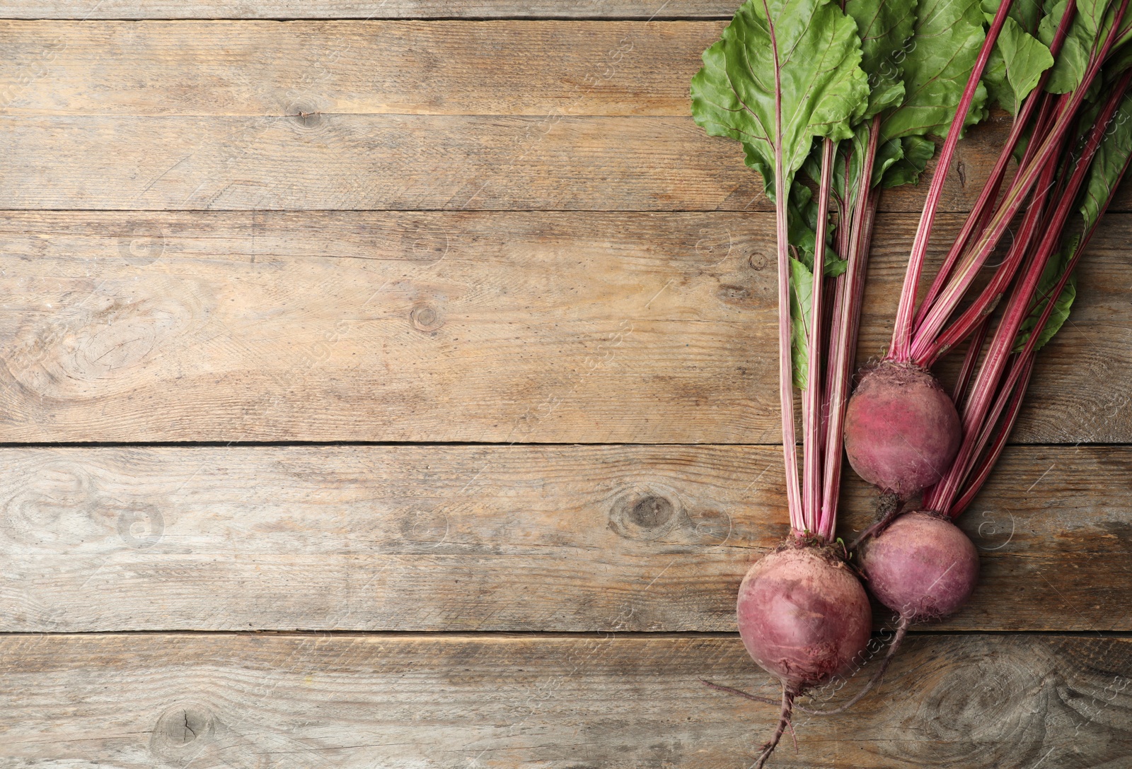 Photo of Raw ripe beets on wooden table, flat lay. Space for text