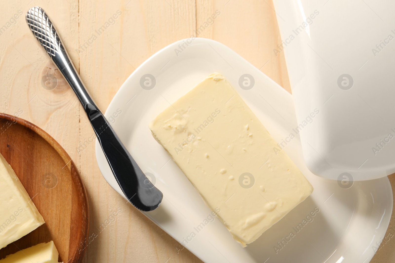 Photo of Tasty butter and knife on wooden table, flat lay