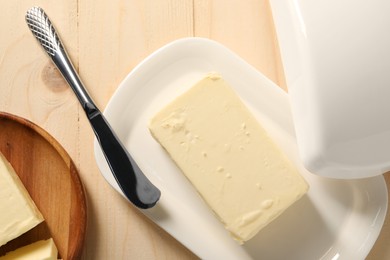 Tasty butter and knife on wooden table, flat lay