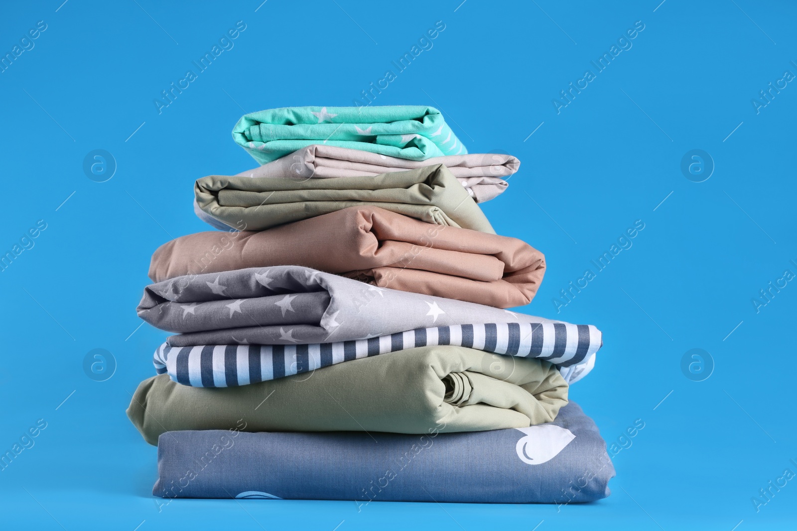 Photo of Stack of clean bed sheets on blue background