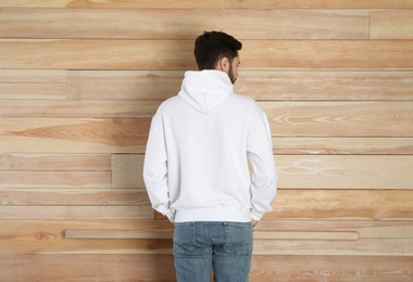 Photo of Young man in sweater at wooden wall. Mock up for design