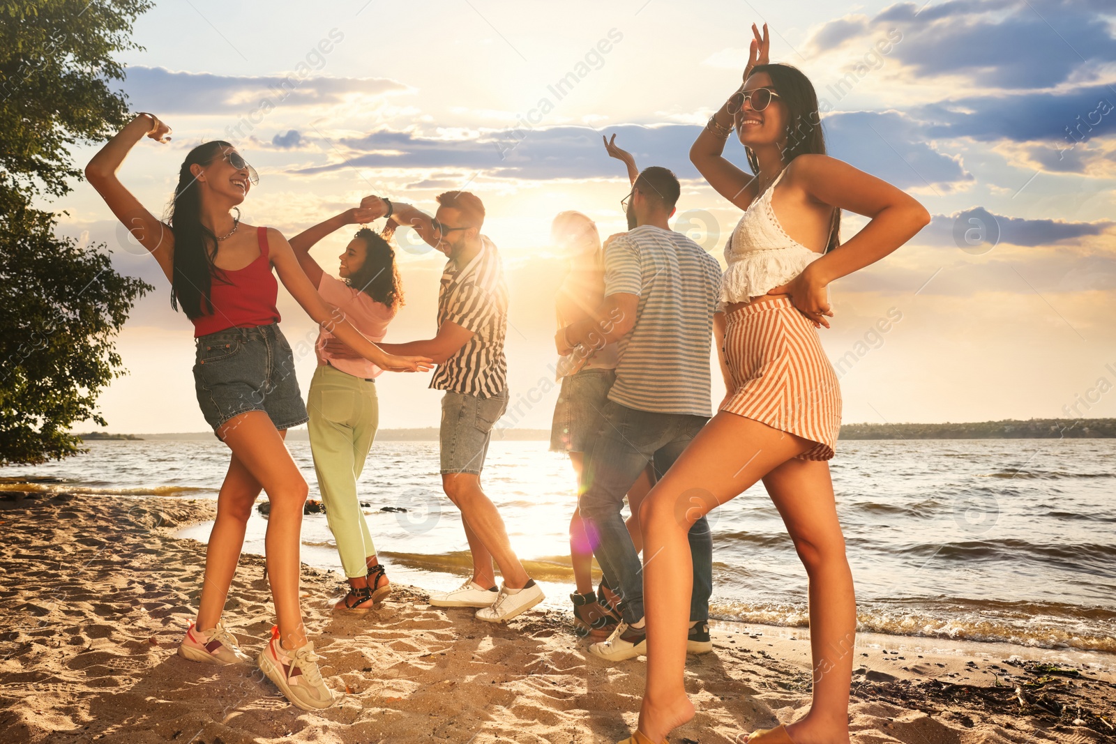 Photo of Group of friends having fun near river at summer party