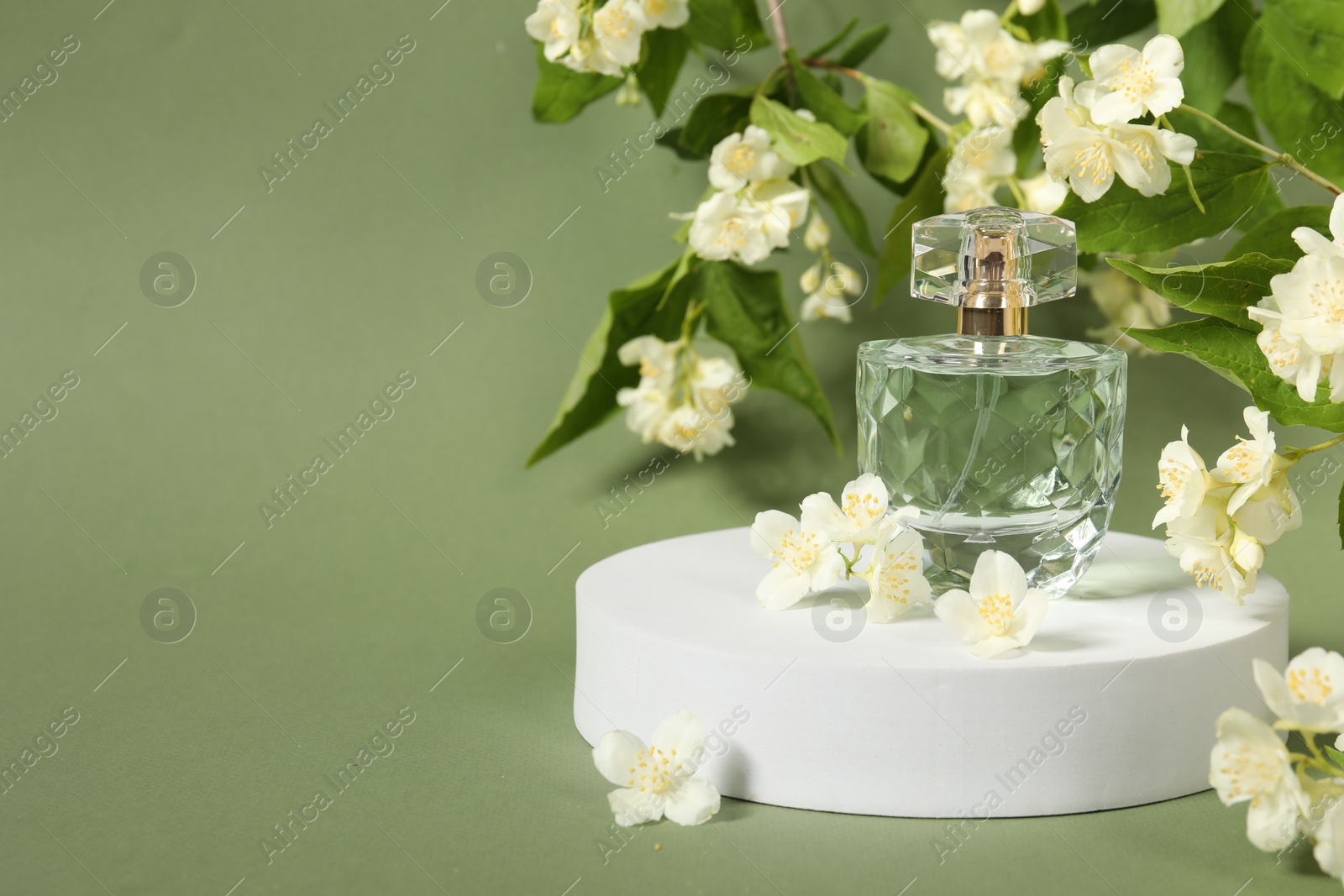 Photo of Presentation of aromatic perfume in bottle and beautiful jasmine flowers against pale green background, space for text