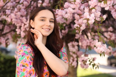 Beautiful woman near blossoming tree on spring day