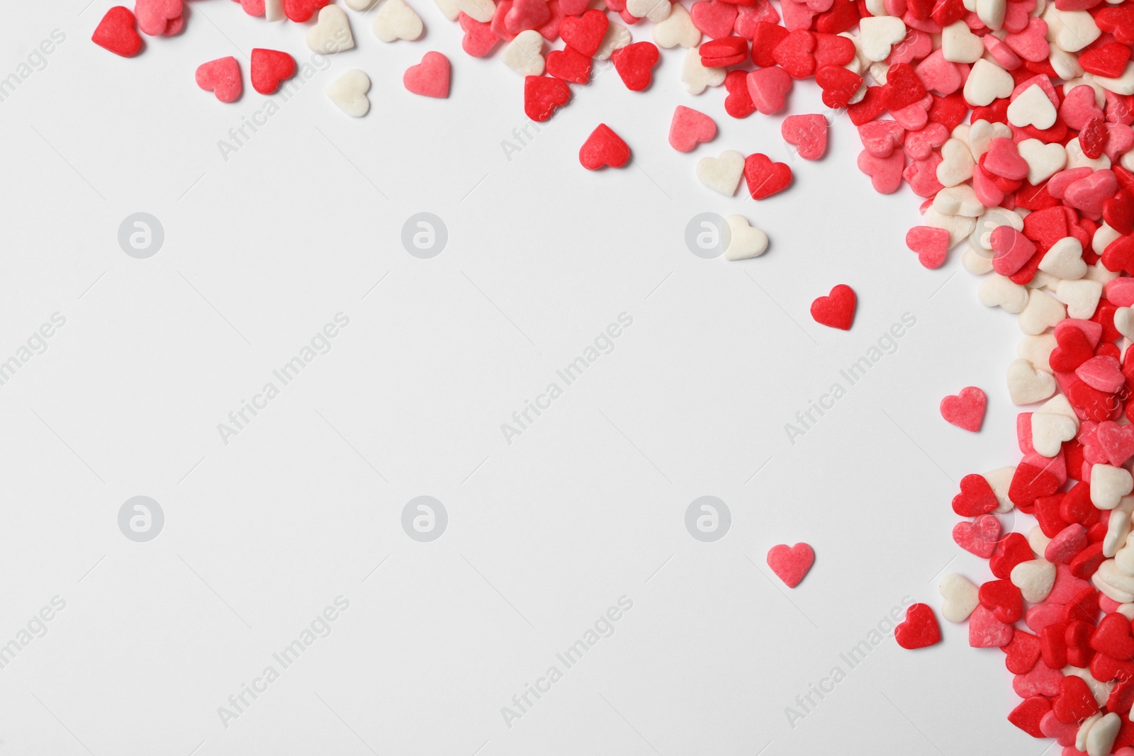 Photo of Bright heart shaped sprinkles on white background, flat lay. Space for text