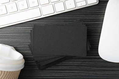 Photo of Blank black business cards, computer keyboard and mouse on wooden table, flat lay. Mockup for design
