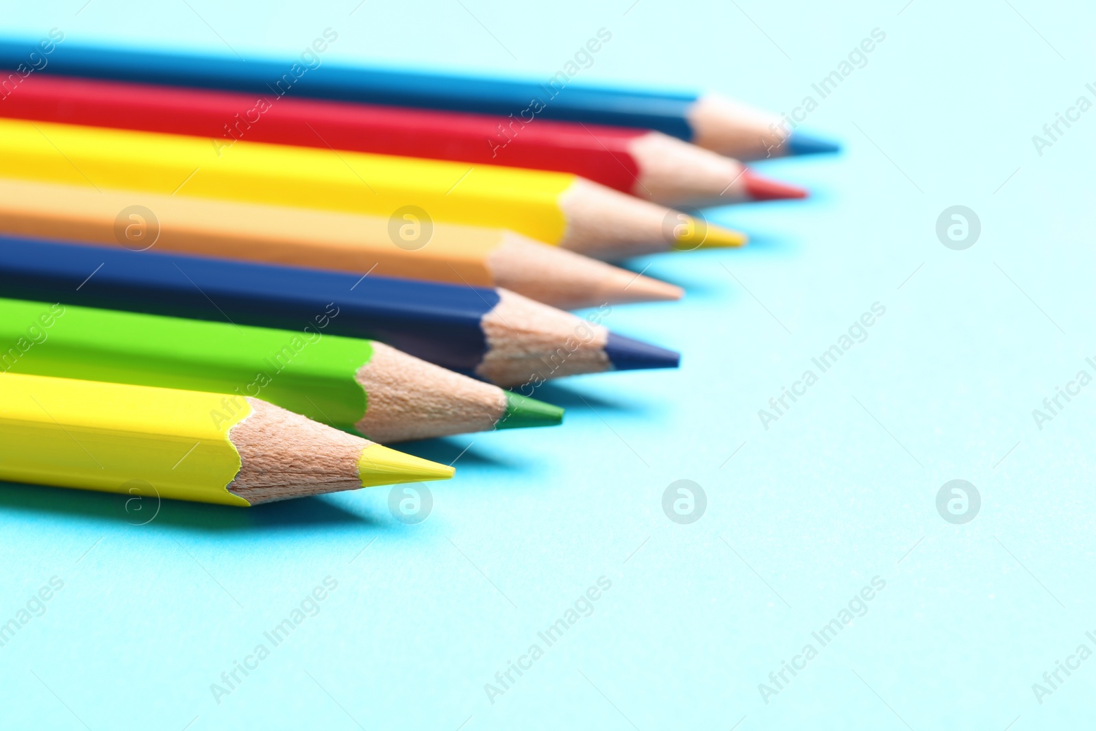 Photo of Colorful pencils on light blue background, closeup