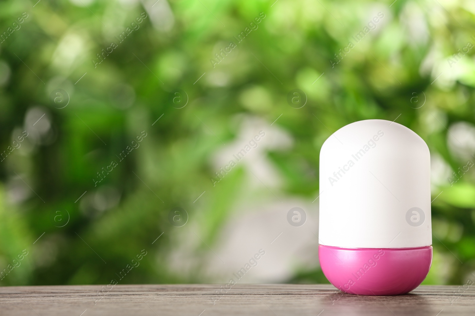 Photo of Deodorant container on wooden table against blurred background. Space for text