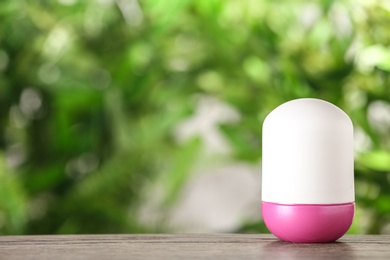 Photo of Deodorant container on wooden table against blurred background. Space for text