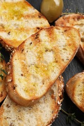 Photo of Tasty bruschettas with oil and thyme on black table, closeup