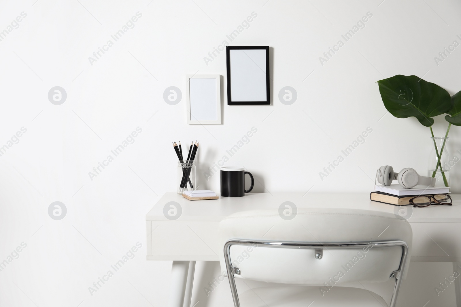 Photo of Comfortable workplace with white desk near wall at home