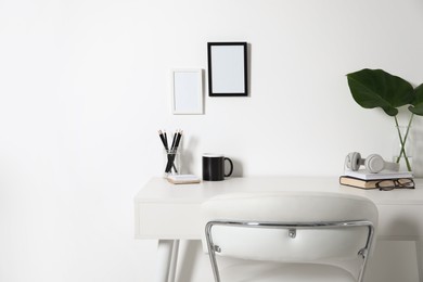 Photo of Comfortable workplace with white desk near wall at home