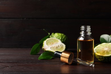 Photo of Bottle of essential oil, pipette and fresh bergamot fruits on wooden table. Space for text