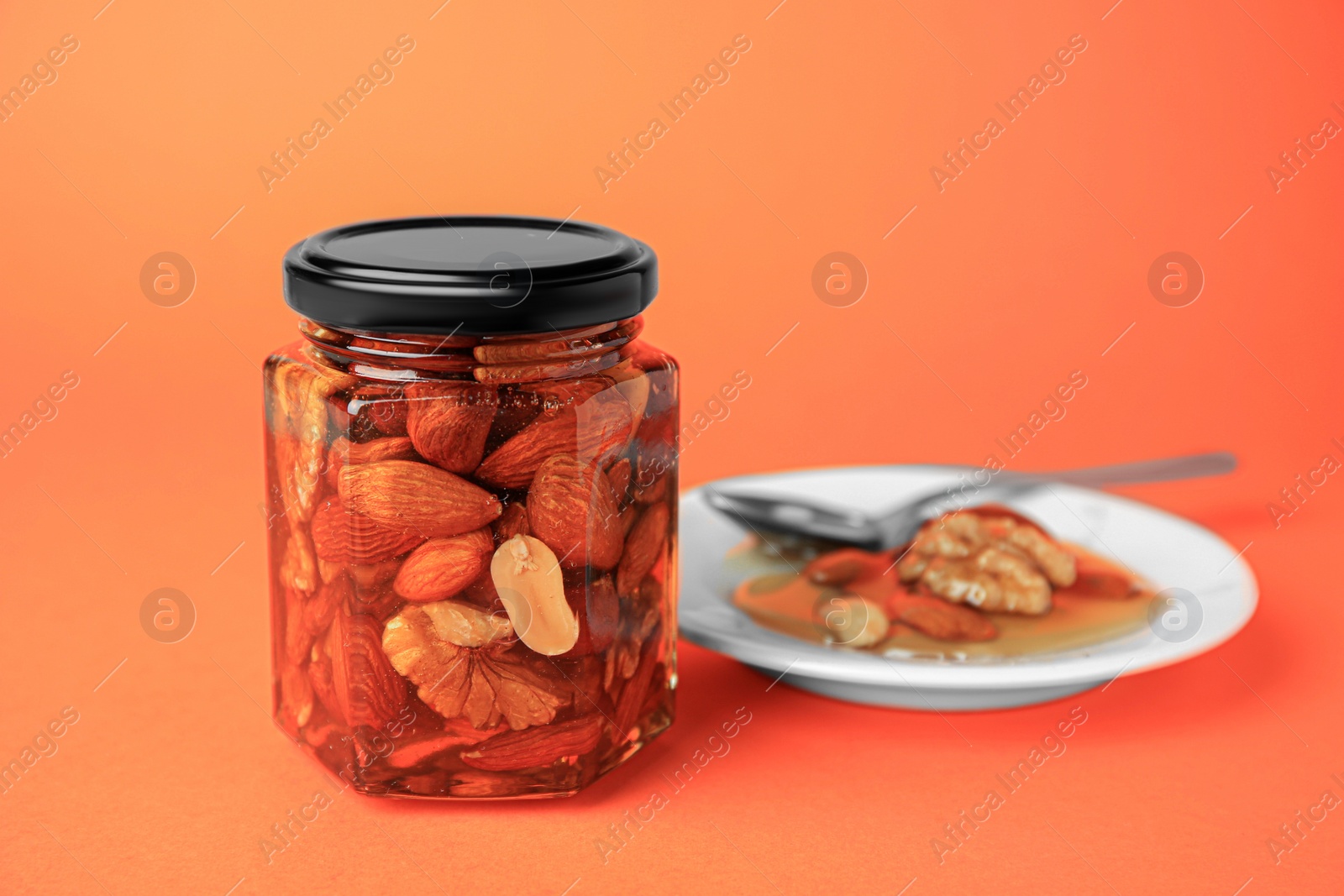 Photo of Different tasty nuts with honey on orange background