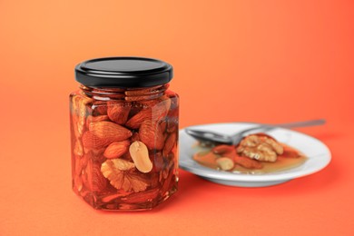 Different tasty nuts with honey on orange background