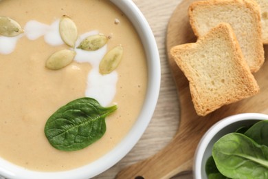 Photo of Healthy cream soup high in vegetable fats, bread and spinach on wooden table, flat lay