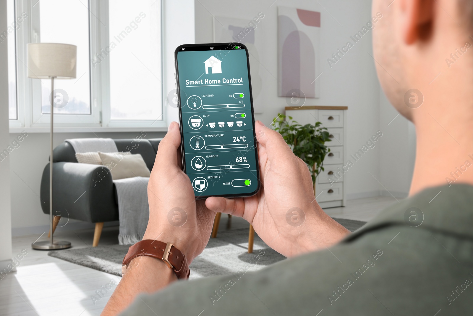 Image of Man using smart home control system via application on mobile phone indoors, closeup