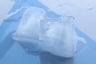 Photo of Crystal clear ice cubes on light blue background, closeup